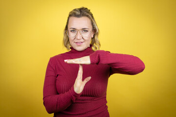 Young caucasian woman wearing casual red t-shirt over yellow background Doing time out gesture with...