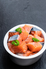 Fresh salmon fillet cubes in clay bowl isolated on white