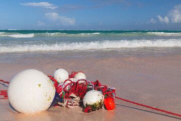 Red white floats and rope lay over wet sandy coast
