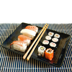 Sushi rolls and chopsticks set on Japanese ceramic plate and bamboo mat
