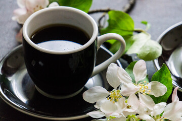 Delicious delicate white-pink marshmallows on the table along with a blossoming apple tree branch and a cup of coffee.