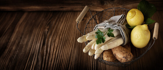 Tied fresh white asparagus on rustic wood. Close-up with short deep of focus. Background for...
