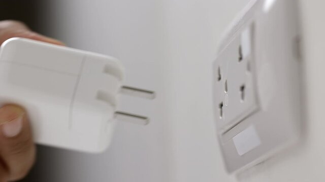 Close up male hand remove the Electric adapter smartphone or laptop plug. Electrical wires and power strips in the house