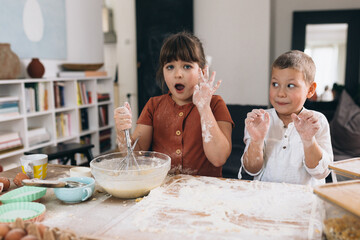 brother and sister baking together at home, making big mess