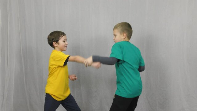 Two athletes in multi-colored t-shirts practice gripping and punching on a light background