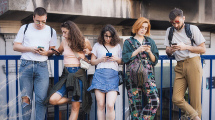 Group of friends using smartphones together. Young people addiction to new technology trends....