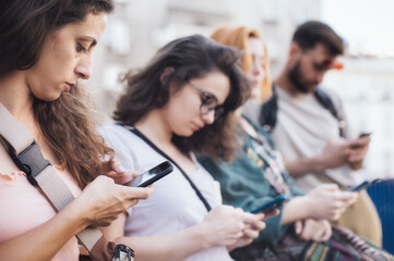 Fototapeta na wymiar Group of friends using smartphones together. Young people addiction to new technology trends. Youth, new generation internet friendship concept. Emotional isolation and depresion