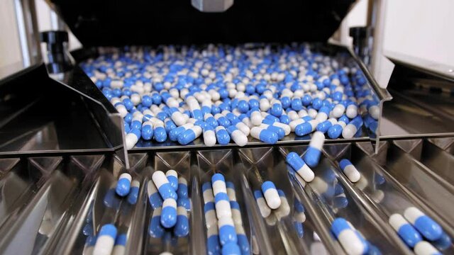 Drug Production. Blue and white pills. Pharmaceutical machinery for medicine production Pills 