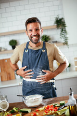 Happy man baking in the kitchen. Man making fresh pasta.