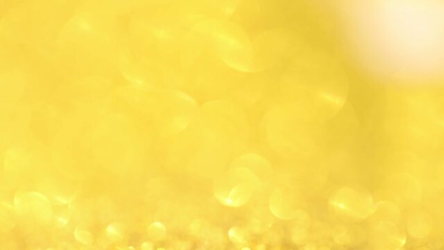 Shimmering gold round lens flares on yellow background. Glittering festive background.