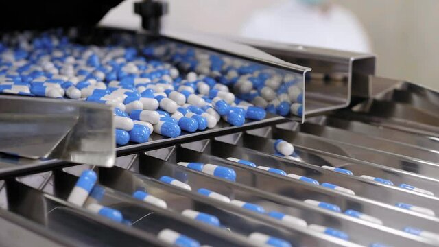 Drug Production. Blue and white pills. Pharmaceutical machinery for medicine production Pills 
