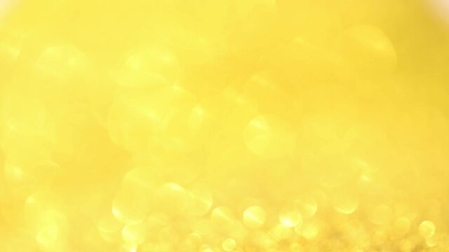Shimmering gold round lens flares on yellow background. Glittering festive background.