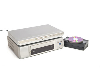 Reproductor de dvd sobre reproductor de vhs junto a cintas de vídeo y cds aislado sobre fondo...