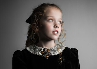 Beautiful young girl in black 1890s English Victorian 18th century child period dress with elegant...