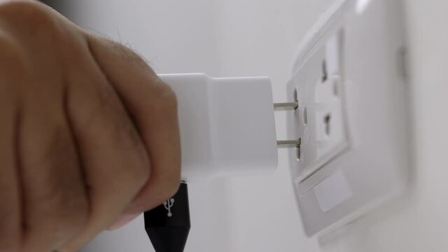 Close up male hand put on the Electric adapter smartphone or laptop plug. Electrical wires and power strips in the house