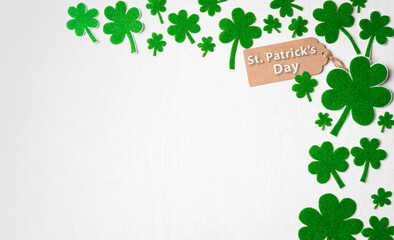Happy St. Patrick's Day concept, St. Patrick's greeting card with green paper clover leaf on white wooden background. Flat lay, top view with copy space.