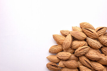A pile of almonds on a white background. Salted fresh nuts in the shell lie in a handful isolated from the background