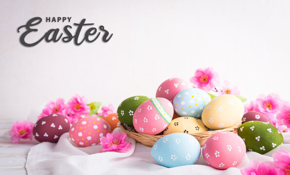 Happy easter decoration concept! Beautiful easter eggs with pink flower on bright white wooden background.