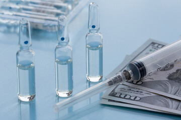Three ampullas, expendable syringe for vaccination and paper money. The concept of insurance medicine, high cost of drugs.