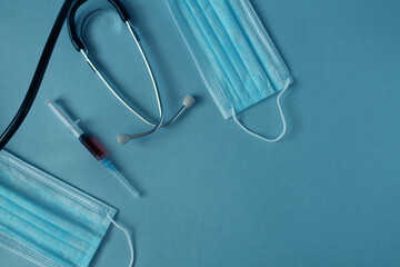 Flatlay medicine background syringe mask stethoscope lie on a blue background with a place for text with a copyspace view from above