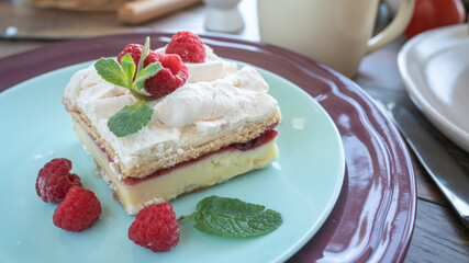 Dessert with fresh raspberries and mint on a plate. Kitchen table. Breakfast. Close-up. Soft focus in the background