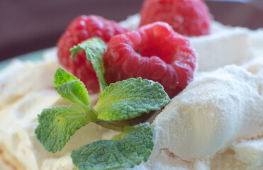 Dessert with fresh raspberries and mint on a plate. Kitchen table. Breakfast. Close-up. Soft focus in the background