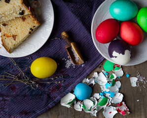 Slices of Easter cake, salt, colored eggs, and egg shells , top view