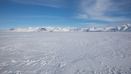Blue and white Arctic backrgound .Windblown winter with mountains and glaciers in the background.