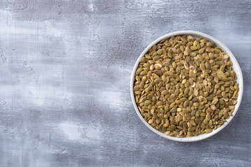 Raw organic pumpkin seeds on a plate. Copy space, top view