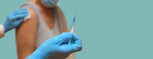 Doctor in medical gloves vaccine elderly woman wearing a facemask for immunization population...