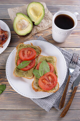 Breakfast with fried eggs and bacon and sandwiches with guacamole sauce