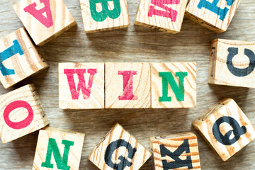 Alphabet letter block in word win with another on wood background