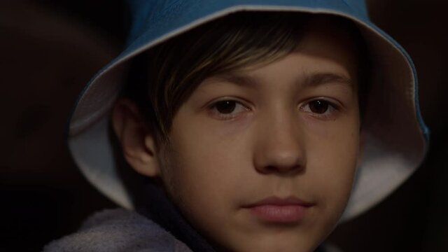 close up of a sad serious boy in hat looking at the camera, indoors