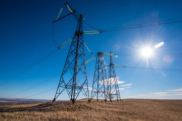 high-voltage power line poles in a field in a blue sunny sky