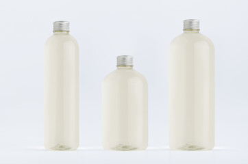 Assortment of three plastic tall, low and thick bottles with pale fresh drink or cosmetic essential oil, silver cap mockup on white background, template.