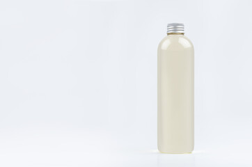 Transparent plastic tall thin bottle with pale fresh drink or cosmetic essential oil, silver cap mockup on white background.