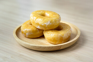 Tasty original icing sugar donuts served on wooden plate. Bakery food close-up photo.