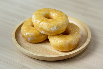 Tasty original icing sugar donuts served on wooden plate. Bakery food close-up photo.