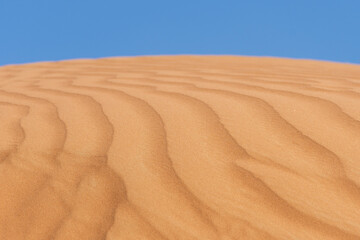 Close up of sand patterns and blue sky background showing textures and shapes of blowing sand in the desert. Sahara Desert or background Concept.