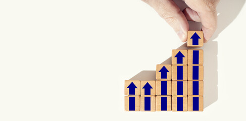 Business growth background. Rising or growing concept. Hand holding a wooden block with up arrow...