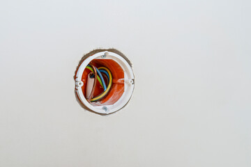 Orange, round installation box mounted in a white wall with an extension installed.