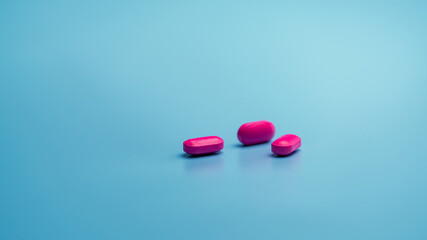 Pink tablets on blue background. Painkiller medicine. Ibuprofen tablets pills. Pharmaceutical industry. Drug for treatment migraine headache. Community pharmacy product. Cancer pain management concept