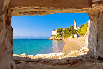 Monastery on pebble beach in Bol view through stone window, - obrazy, fototapety, plakaty