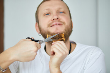 Handsome man in white t-shirts cutting beard, moustache personally himself