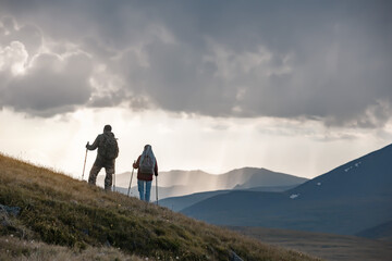 Obraz premium Two hikers stands on mountain slope against sunset