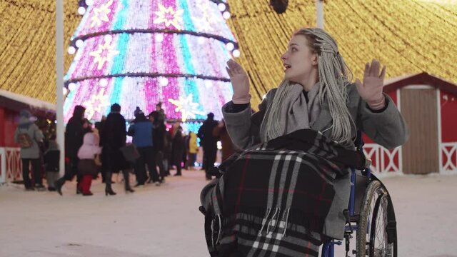 Young woman in a wheelchair at Christmas party on the streets - dancing and having fun