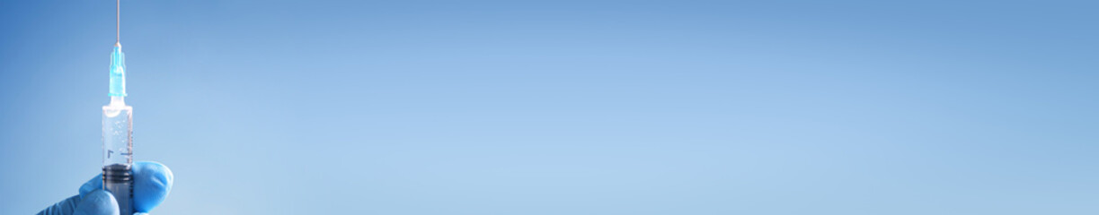 Doctor in blue latex gloves fill in syringe with medicine from glass vial. Long banner