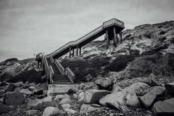 Grayscale shot of stairs leading to the top of a big rock scale