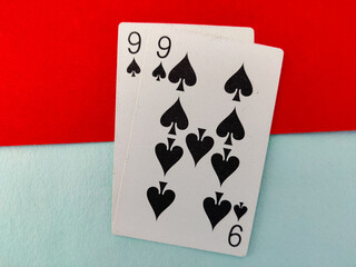 Nine of spade playing cards in two numbers isolated on red and green background. 99