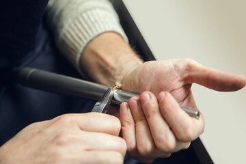 Rounding. Close up hands of jeweller, goldsmiths making of golden ring with gemstone using...